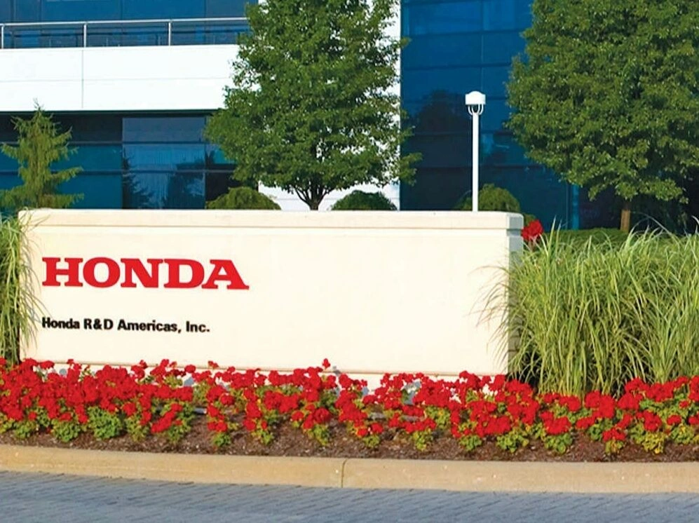 Glass entrance lobby sign at Honda R&D Americas facility featuring blue Honda logo and 'Honda R&D Americas, Inc.' lettering